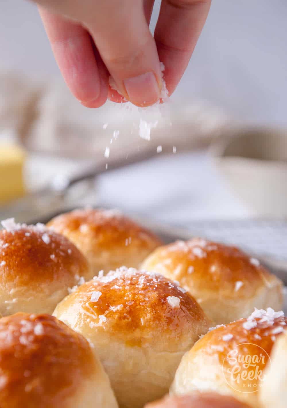 sprinkling seasalt onto freshly buttered homemade dinner rolls