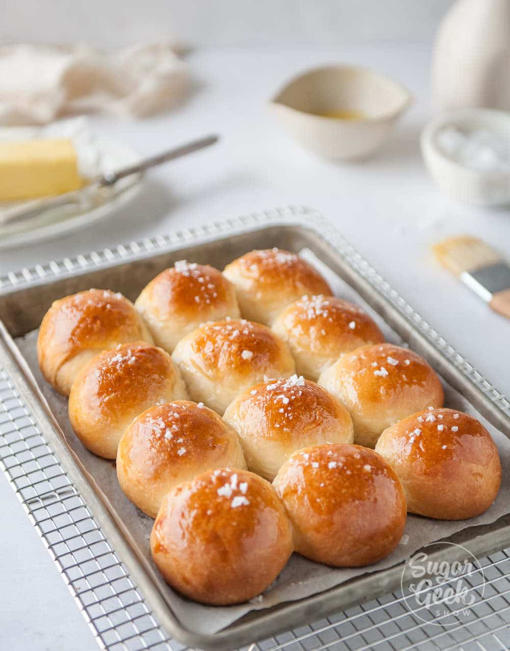 homemade dinner rolls on a pan with butter and salt in the background 