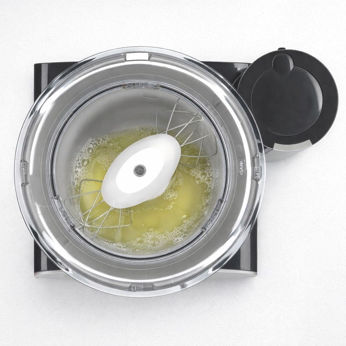 Egg whites in the bowl of a mixer with the whisk attachments attached.