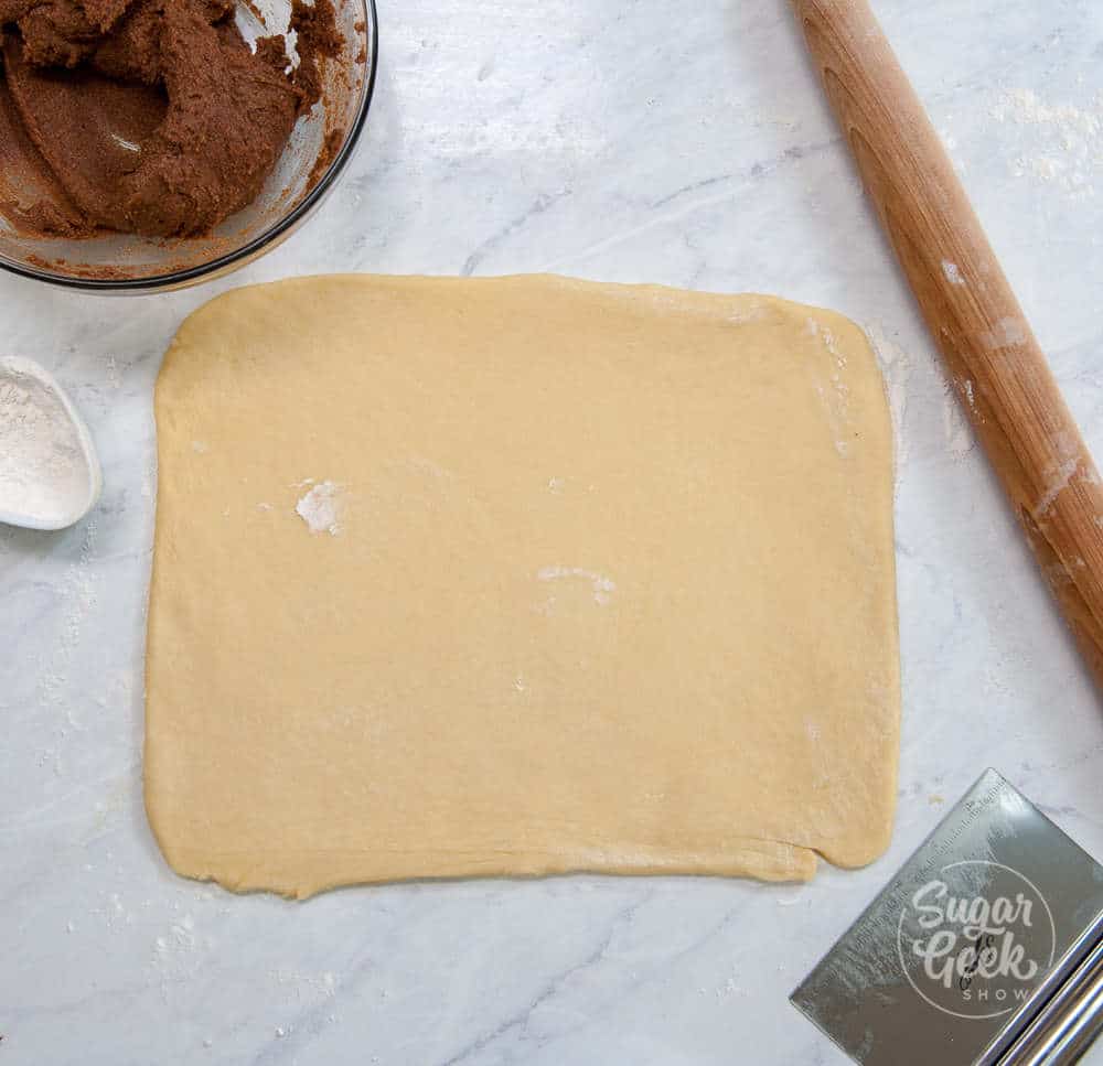 cinnamon roll dough being rolled out