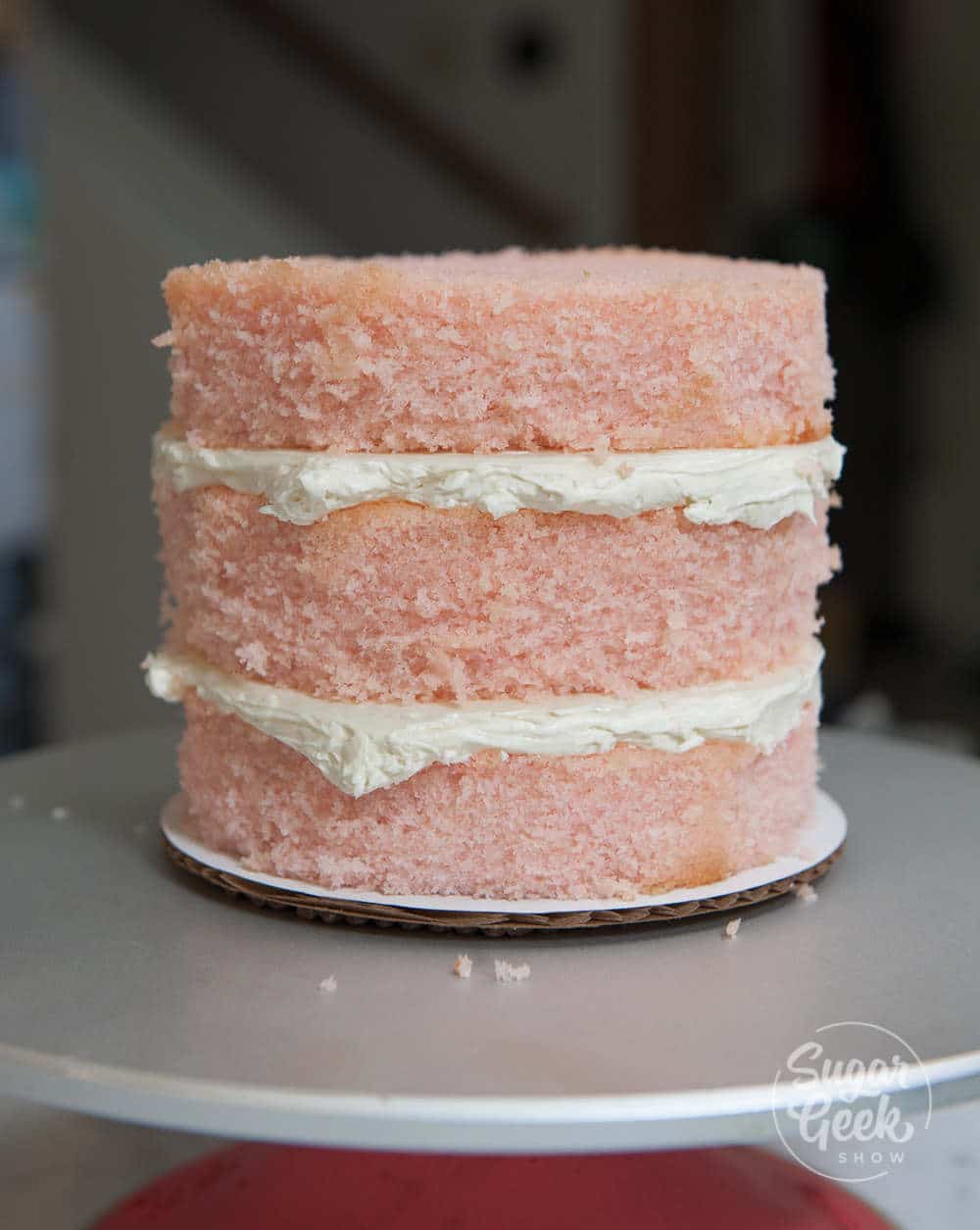 three layers of pink velvet cake with whipped cream in between the layers