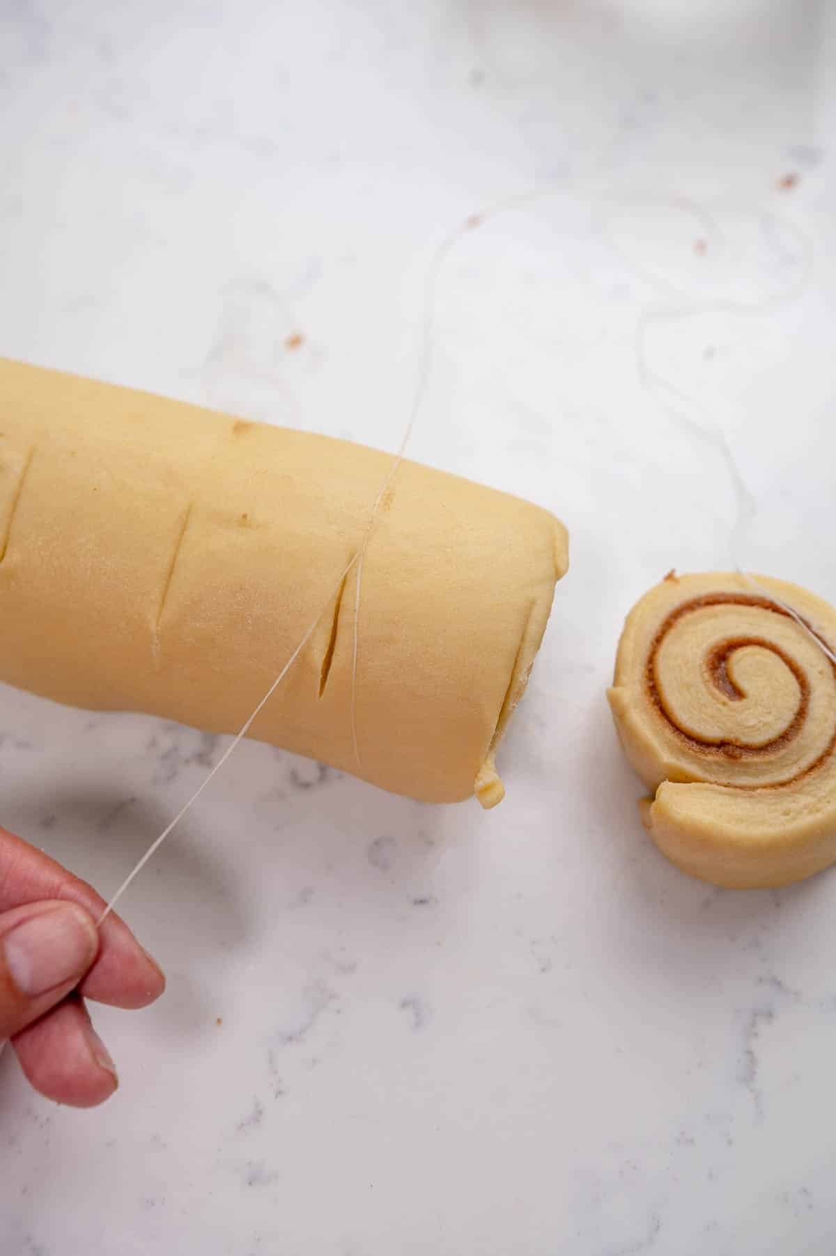 close up of cinnamon rolls being cut with dental floss