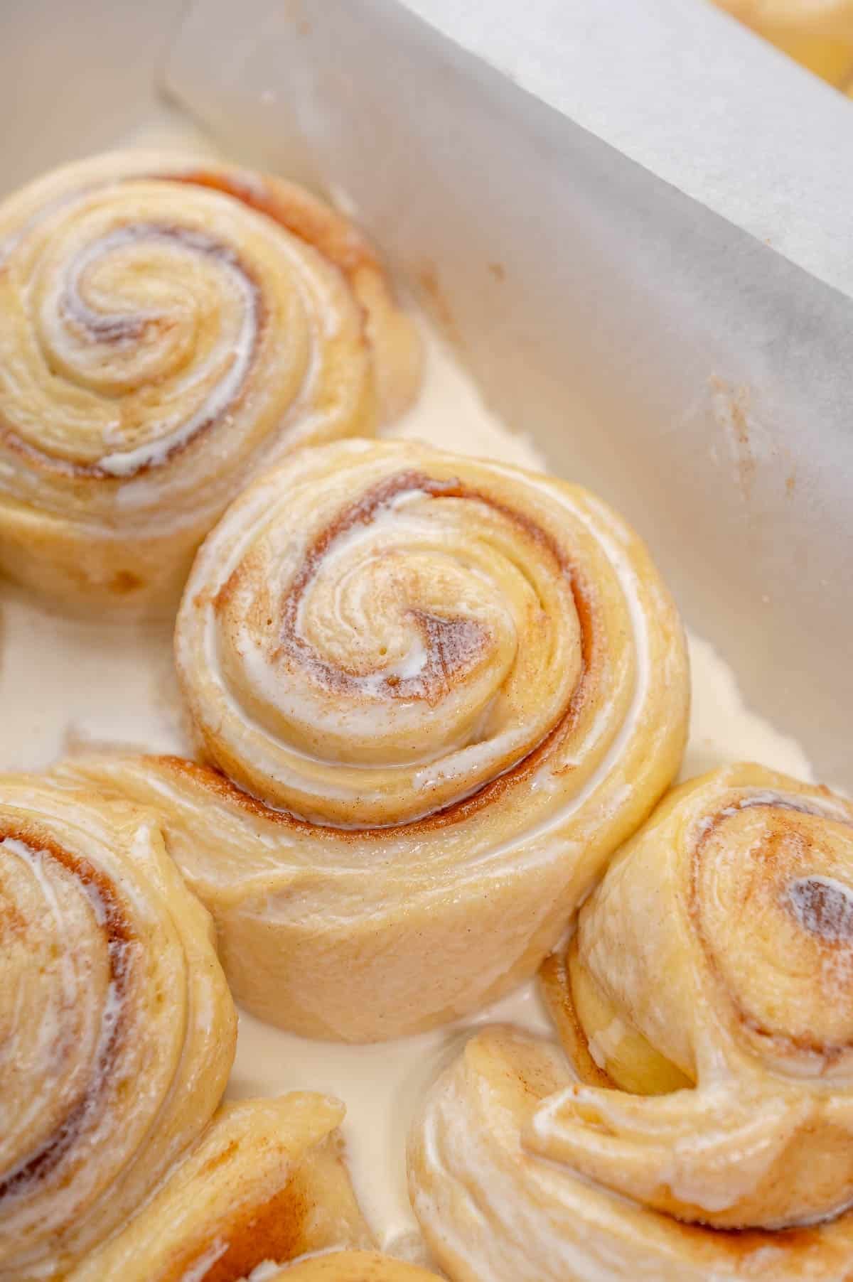 puffy proofed cinnamon rolls touching each other in a pan