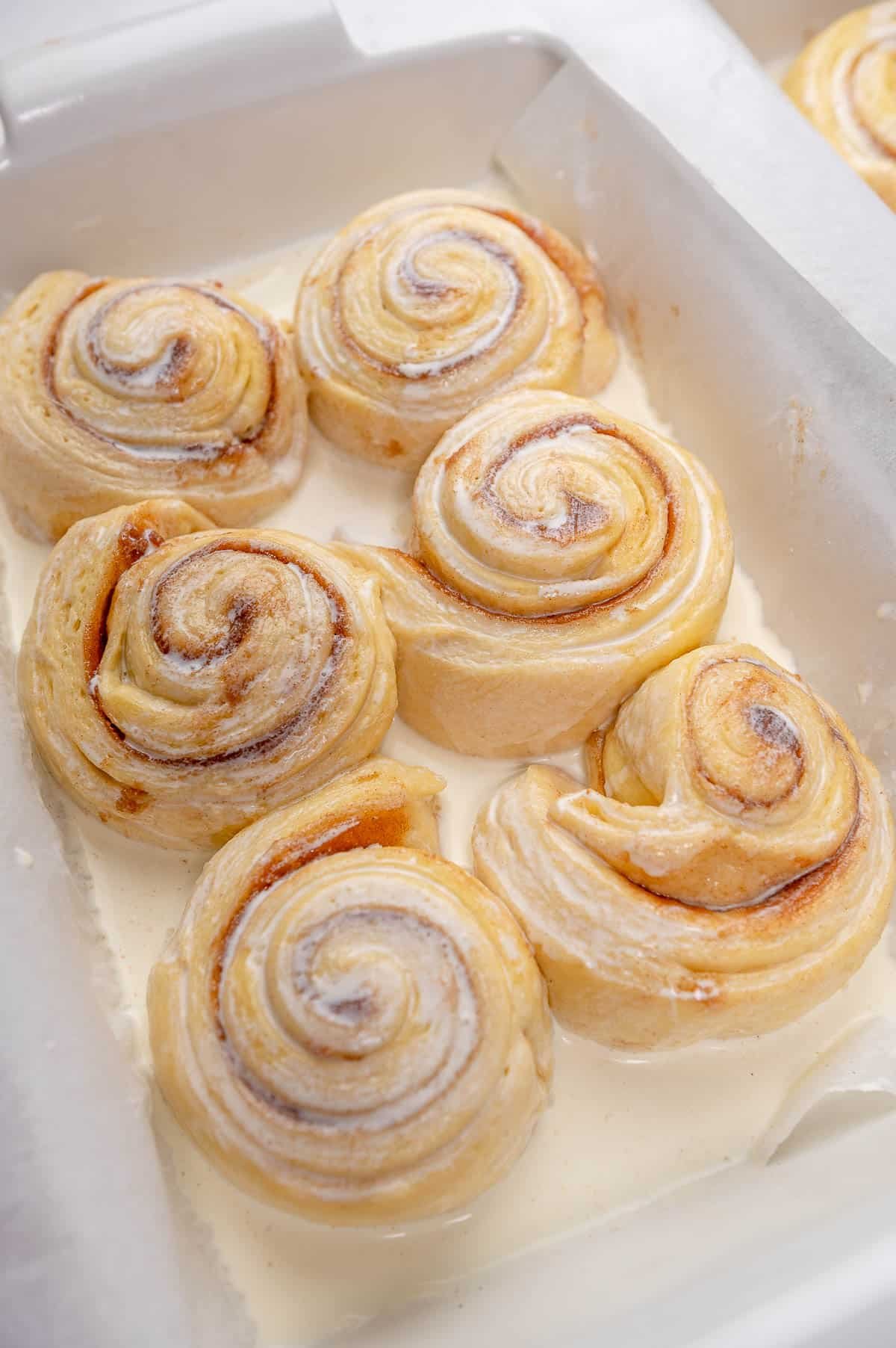 close up of cinnamon rolls in cream in a pan