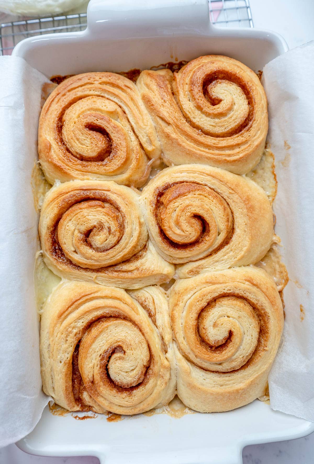 close up of baked cinnamon rolls in a white pan