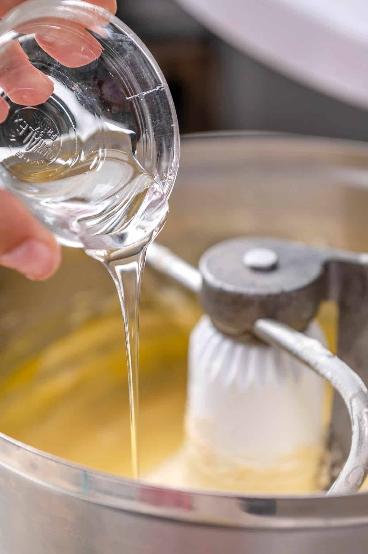 pouring corn syrup into cinnamon roll dough in a stand mixer