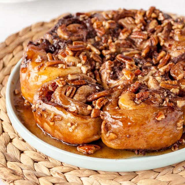 homemade sticky buns on a blue plate on top of a natural woven placemat