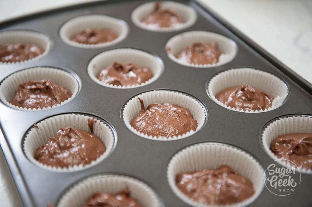 cupcake pan with white liners filled halfway with chocolate cupcake batter