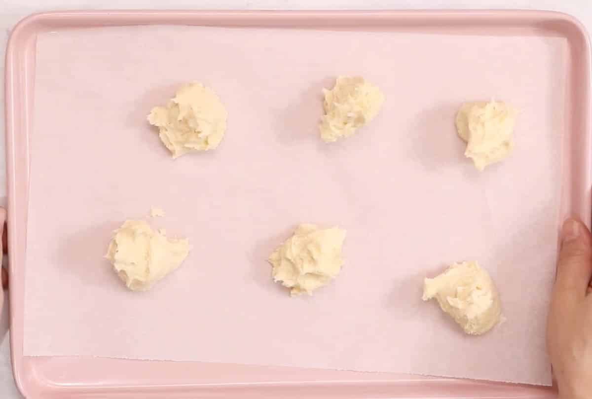 Lofthouse cookie dough scooped onto a pink cookie sheet.