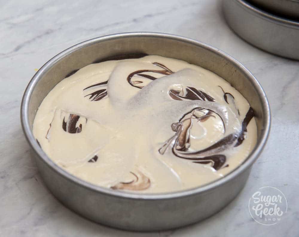 Vanilla and chocolate cake batter in a cake pan and lightly marbled together