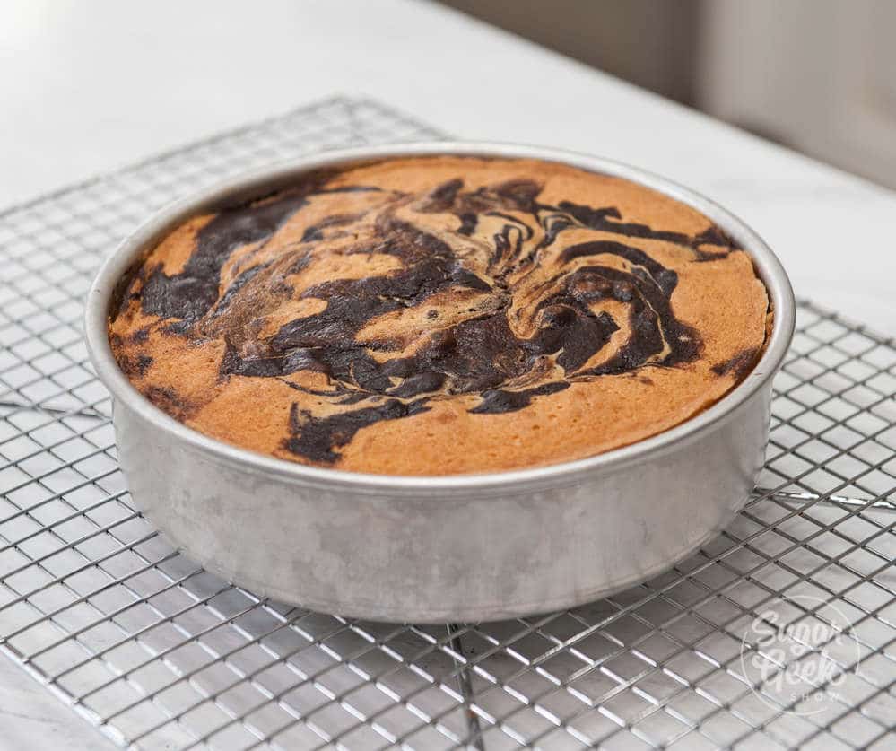 marble cake freshly baked in a cake pan, cooling on a wire rack