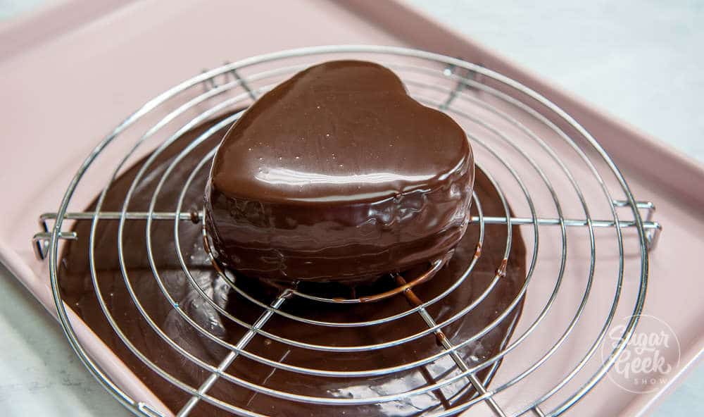 mini cheesecake heart being glazed with chocolate ganache