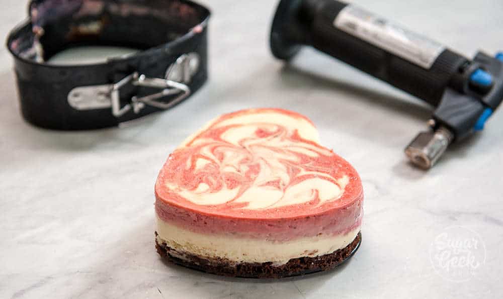 mini cheesecake being removed from the pan with a kitchen torch