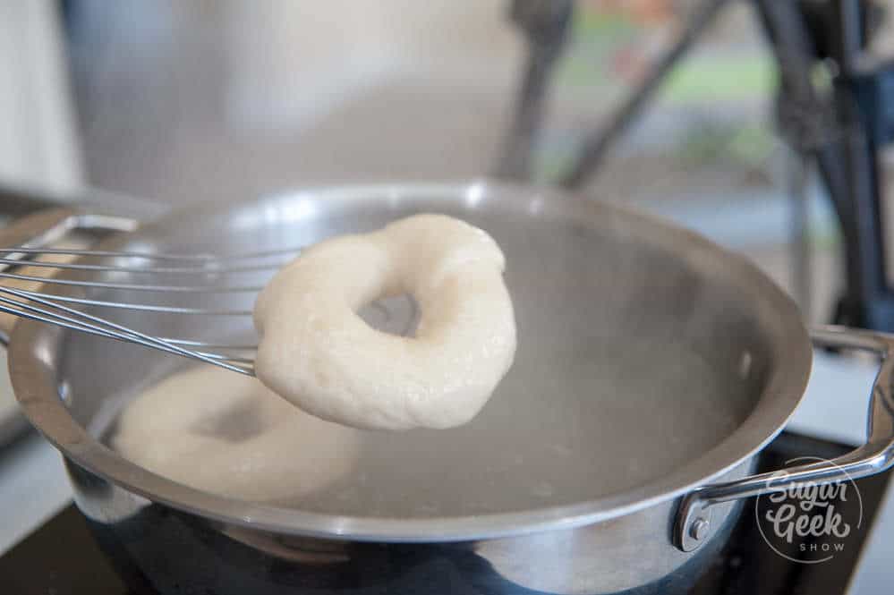 homemade bagel on whisk over boiling water