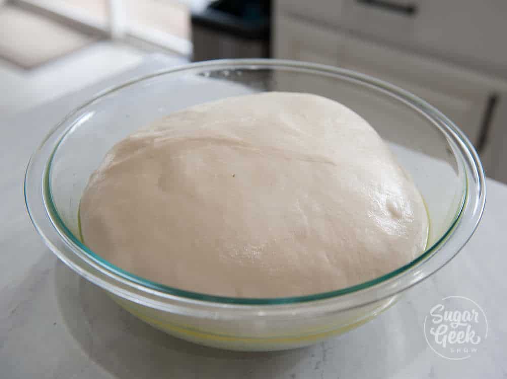 bagel dough proofing in a clear bowl