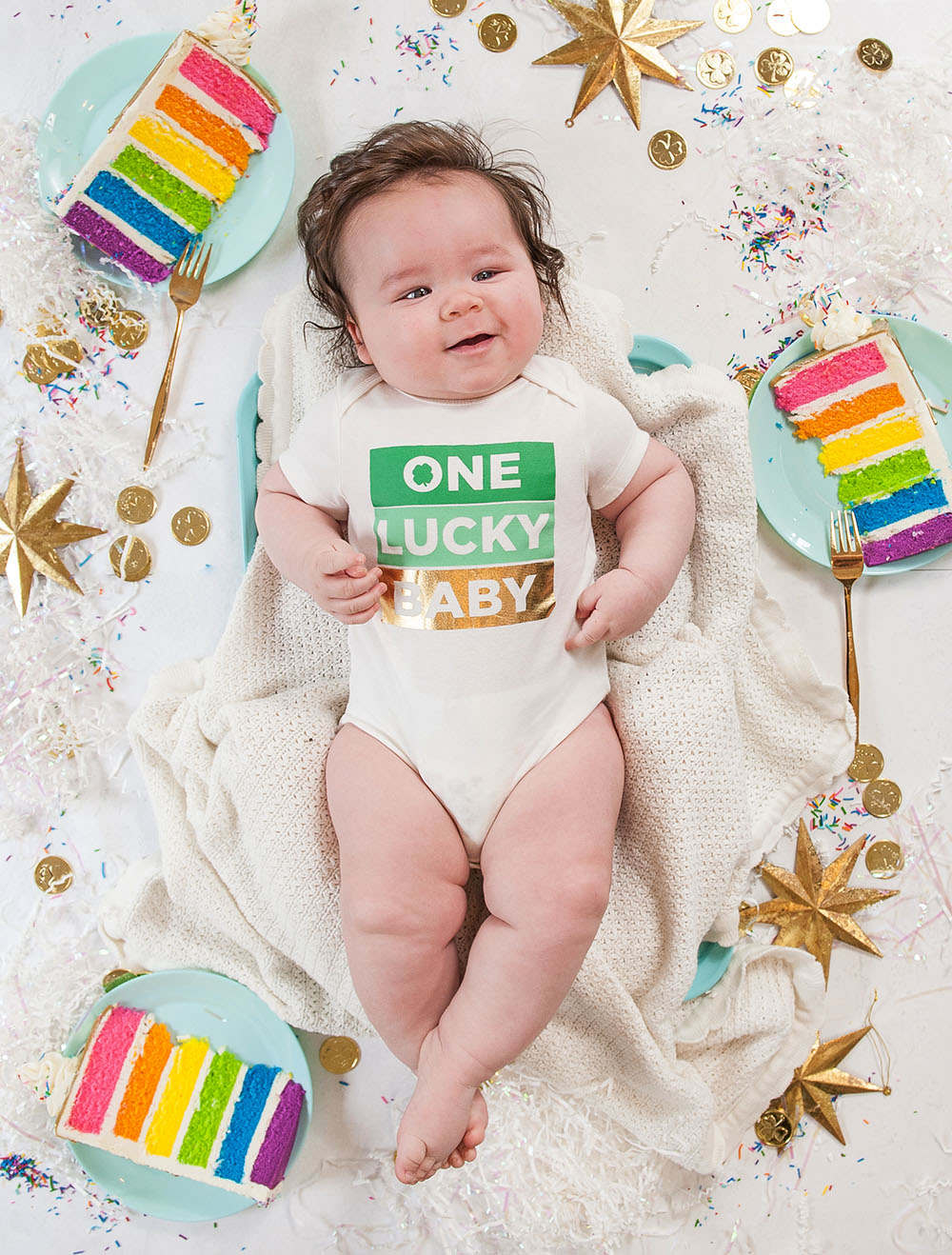 6 month old baby boy on white background with rainbow cake slices around him