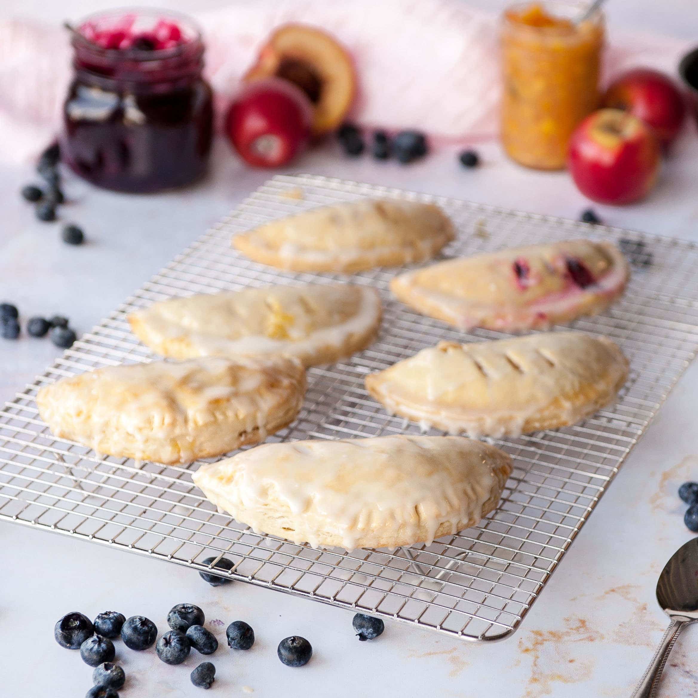hand pies on a cooling rack on white background with blueberries and fresh fruit in the background