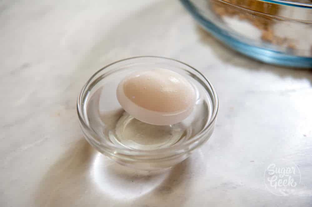 egg in a clear bowl of hot water on white background