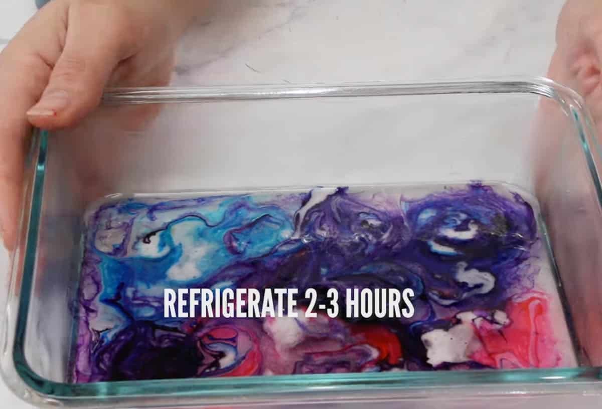 Hands holding kohakutou mixture in a rectangular glass dish.