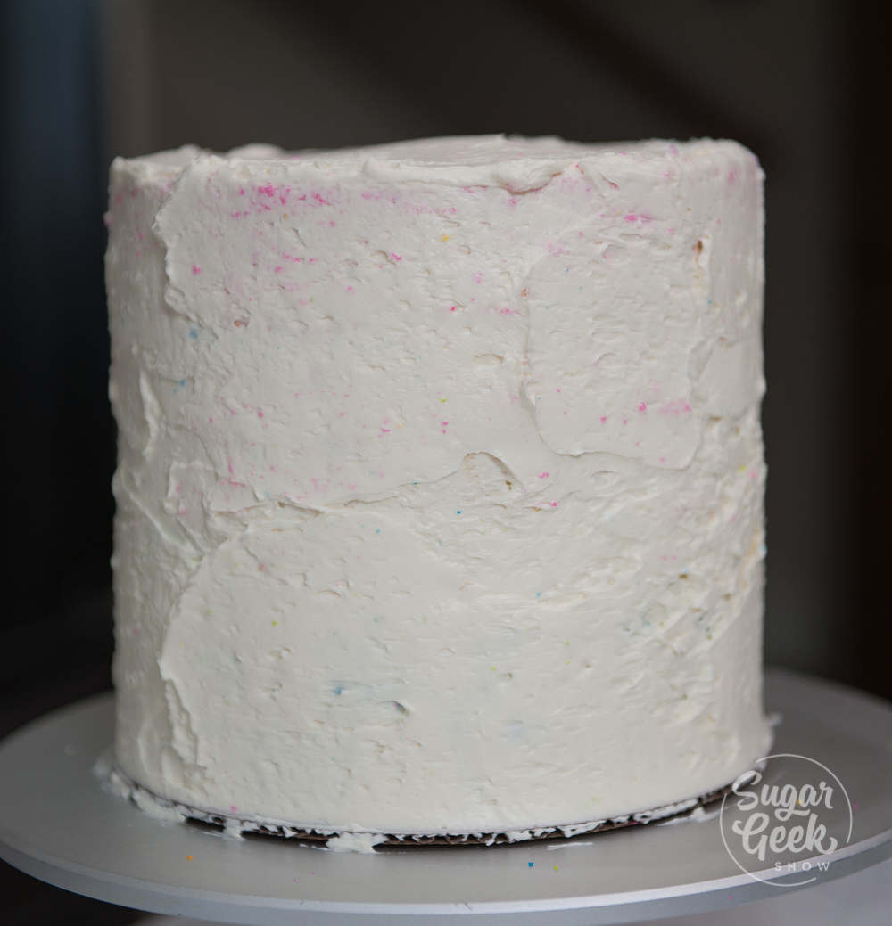 rainbow cake with layer of frosting for the crumb coat