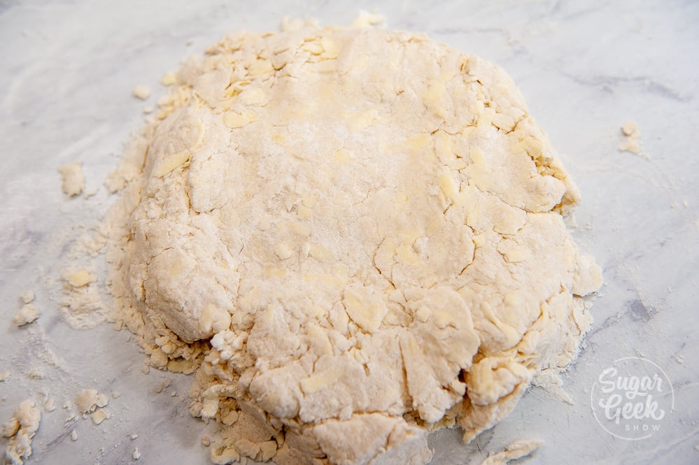 rough biscuit dough pressed together on a white countertop