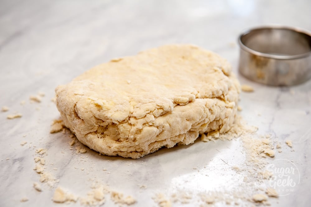 rough biscuit dough folded in half on white countertop