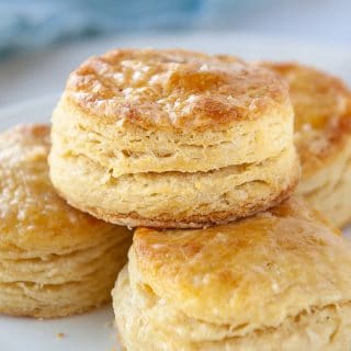 closeup of flaky buttermilk biscuit on top of other biscuits