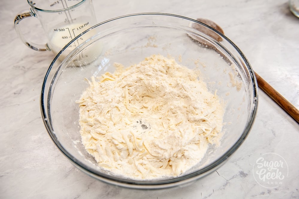 flour, sugar, salt, baking powder and baking soda in a clear bowl combined with shredded cold butter