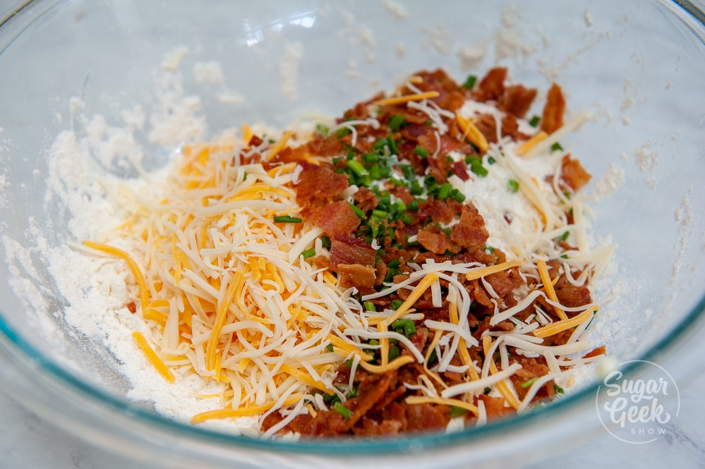 shredded cheese, bacon, and chives in mixing bowl with flour butter mixture