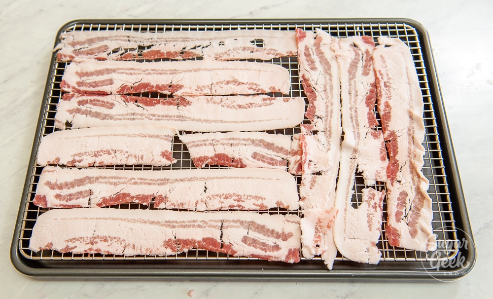 strips of raw bacon arranged on a cooling rack on metal sheet pan