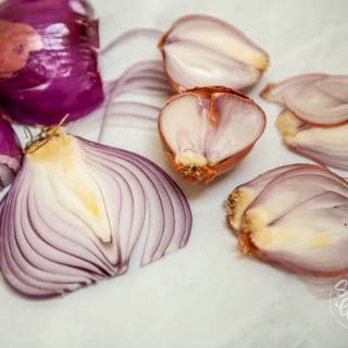 thinly sliced red onions and shallots on white table