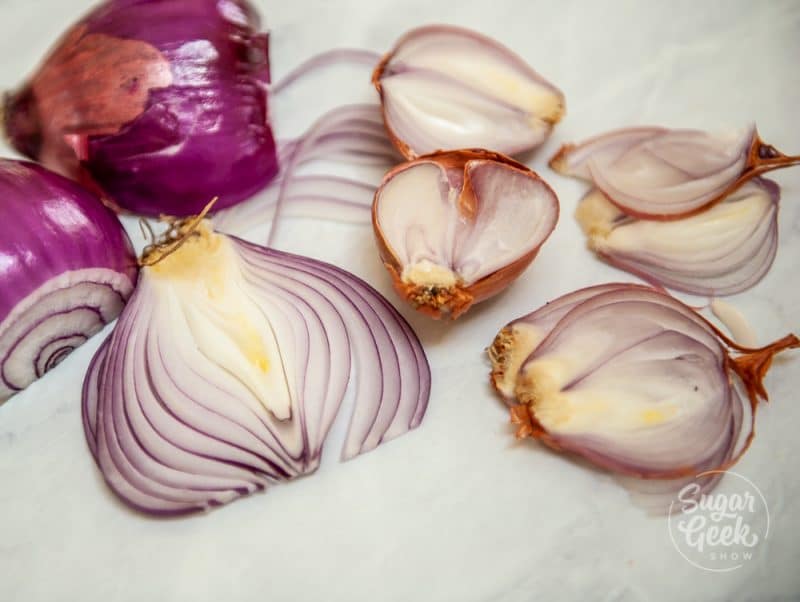 thinly sliced red onions and shallots on white table