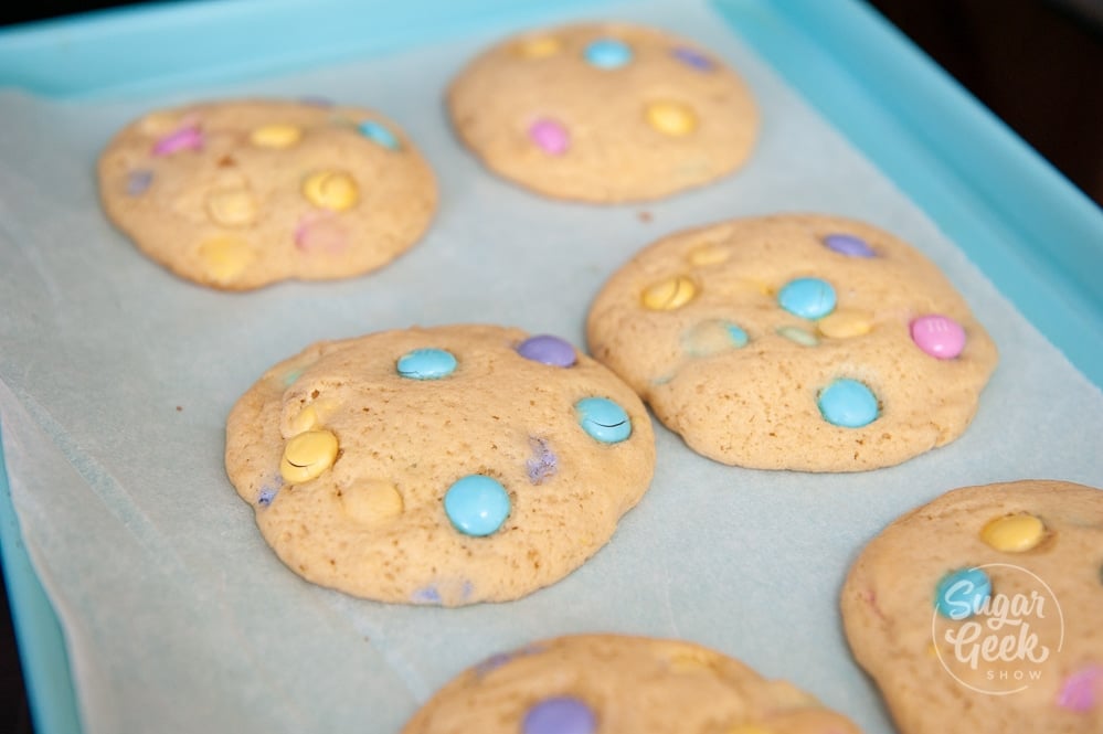 freshly baked M&M cookies on blue cookie sheet