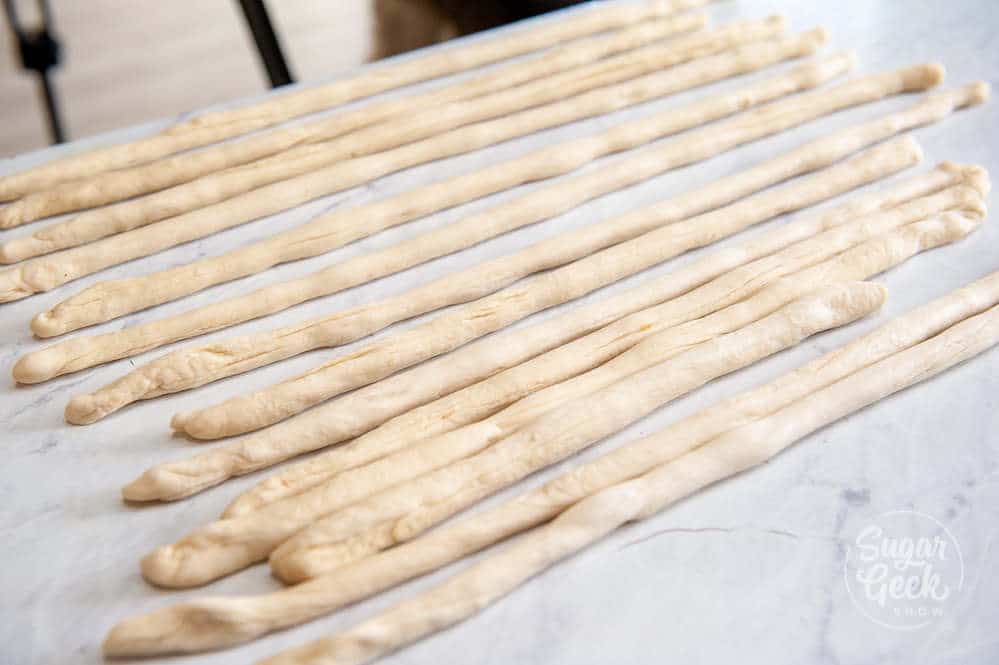 pretzel dough rolled out to 22" long on white countertop