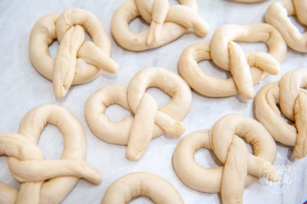 soft pretzels shaped and placed on parchment paper ready to boil