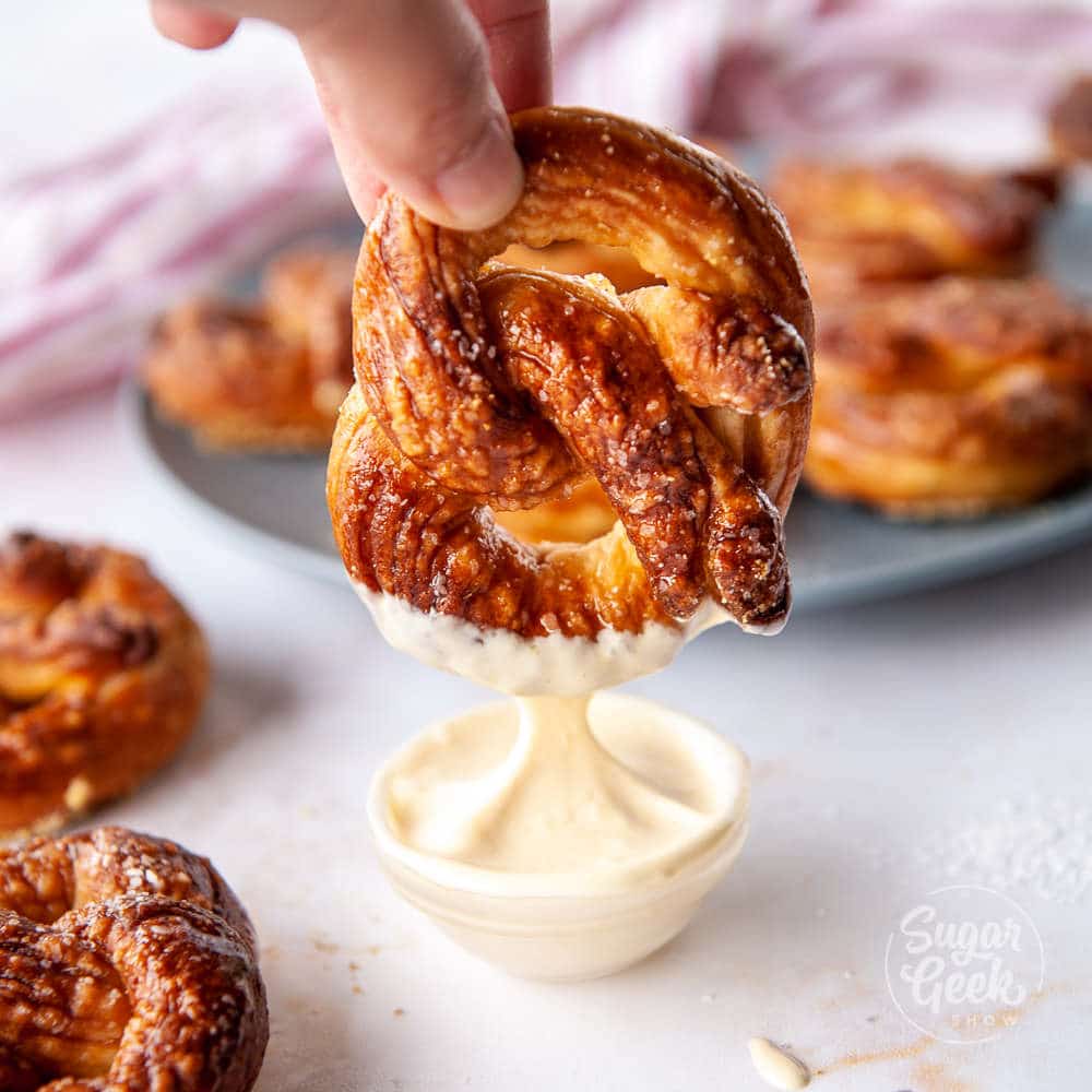 soft pretzel being dipped in mustard sauce