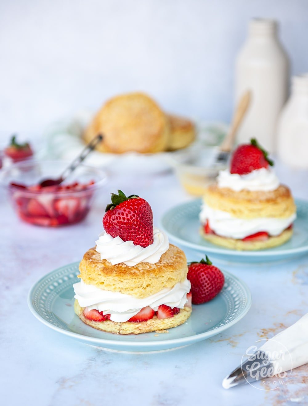 strawberry shortcake on blue plates with ingredients in background