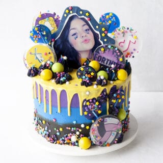 Cake with all kinds of lollipops, logos and icons, a topper of a birthday girl and a ganache drip with sprinkles