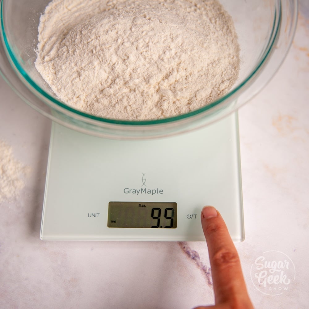 flour in a clear bowl on top of a digital kitchen scale