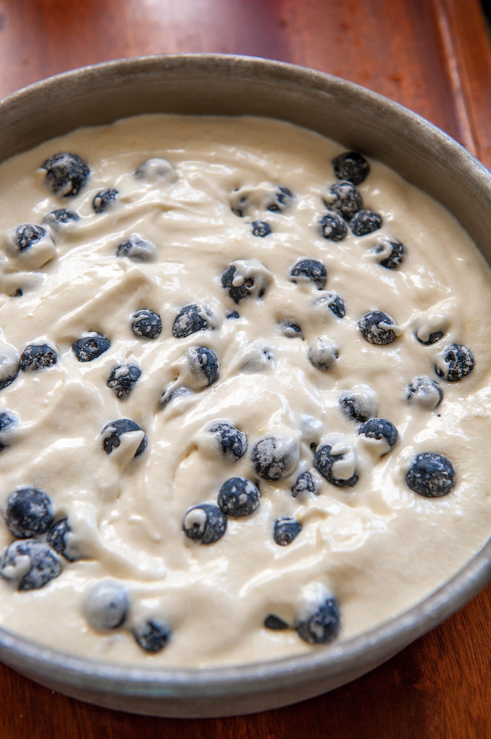 blueberries on top of cake batter in a cake pan