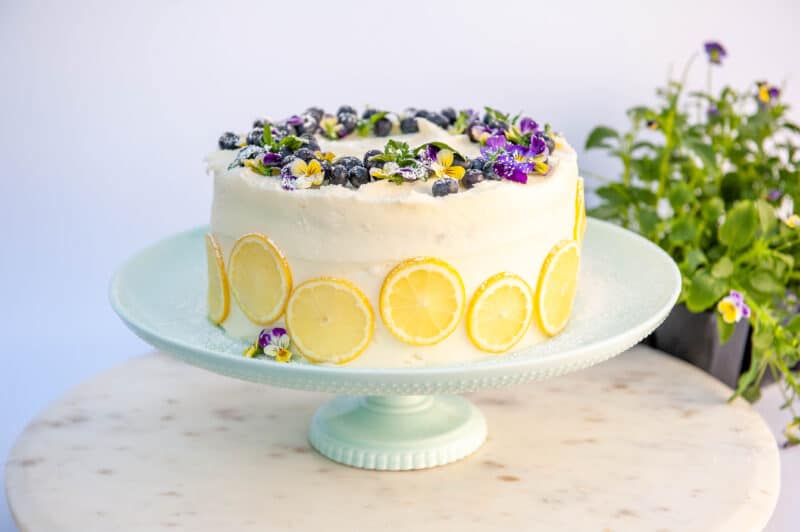 lemon blueberry layer cake on light blue cake stand