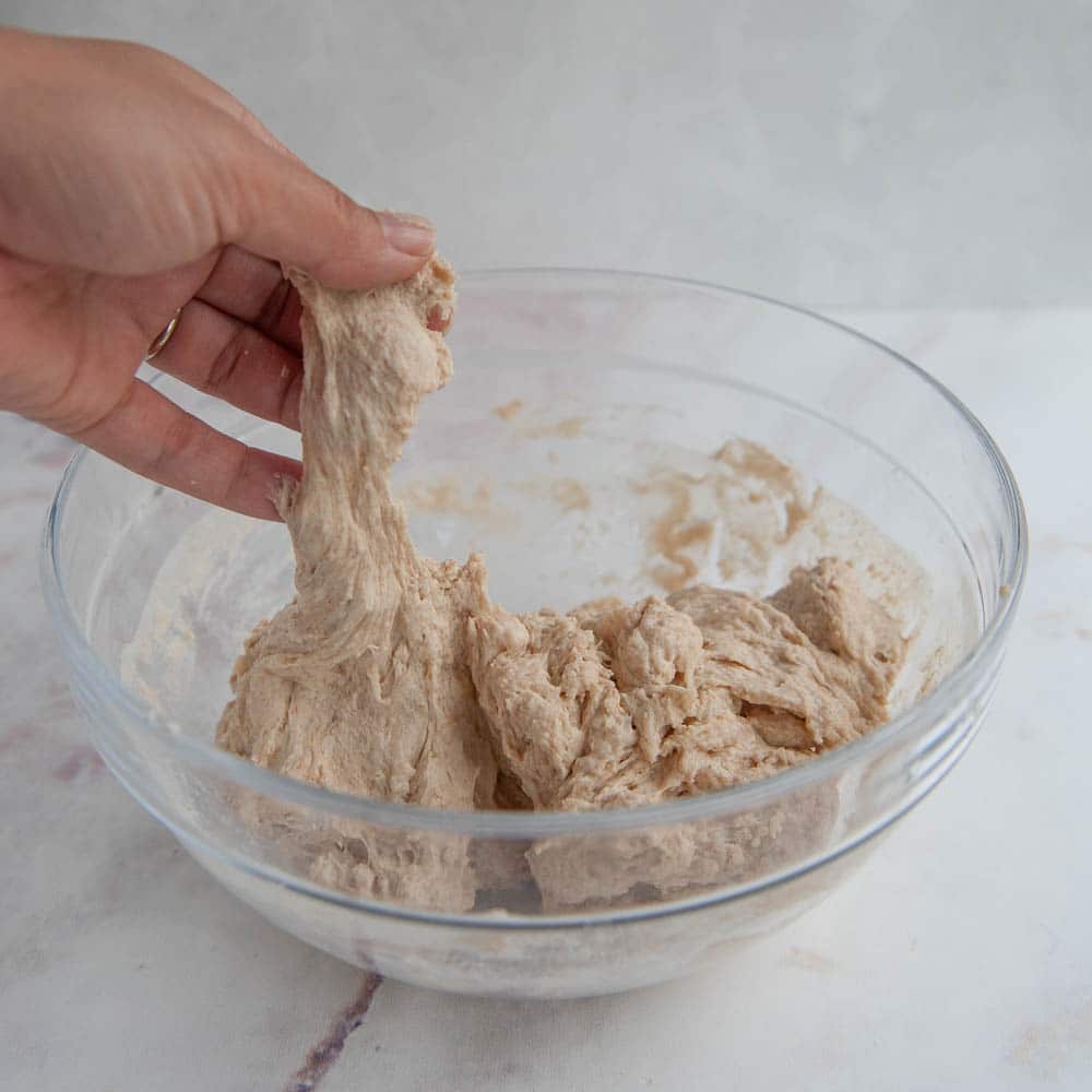 Sourdough bread ingredients mixed together in a clear glass bowl.