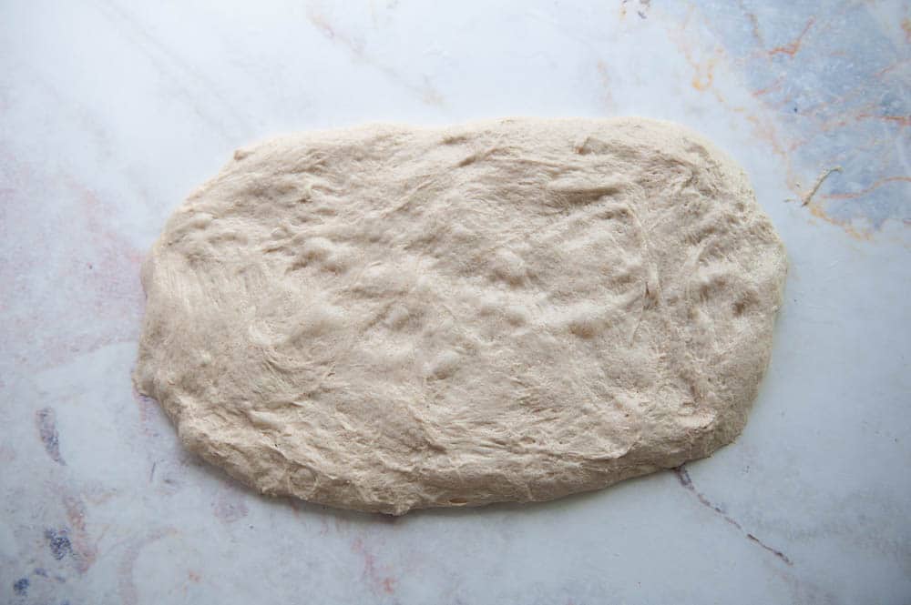 sourdough bread dough spread out on a flat surface