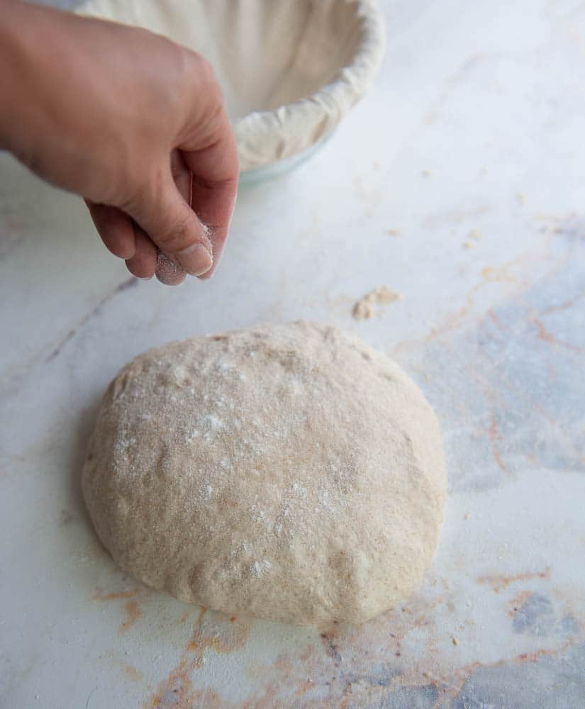 Hand dusting sourdough bread dough with flour.