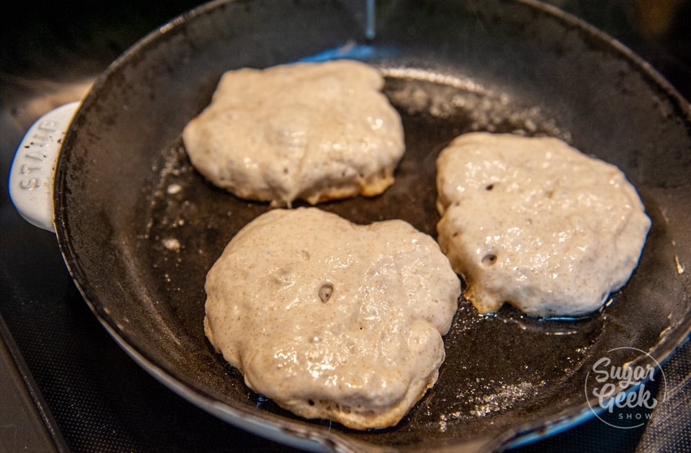 sourdough pikelets cooking in a cast iron pan