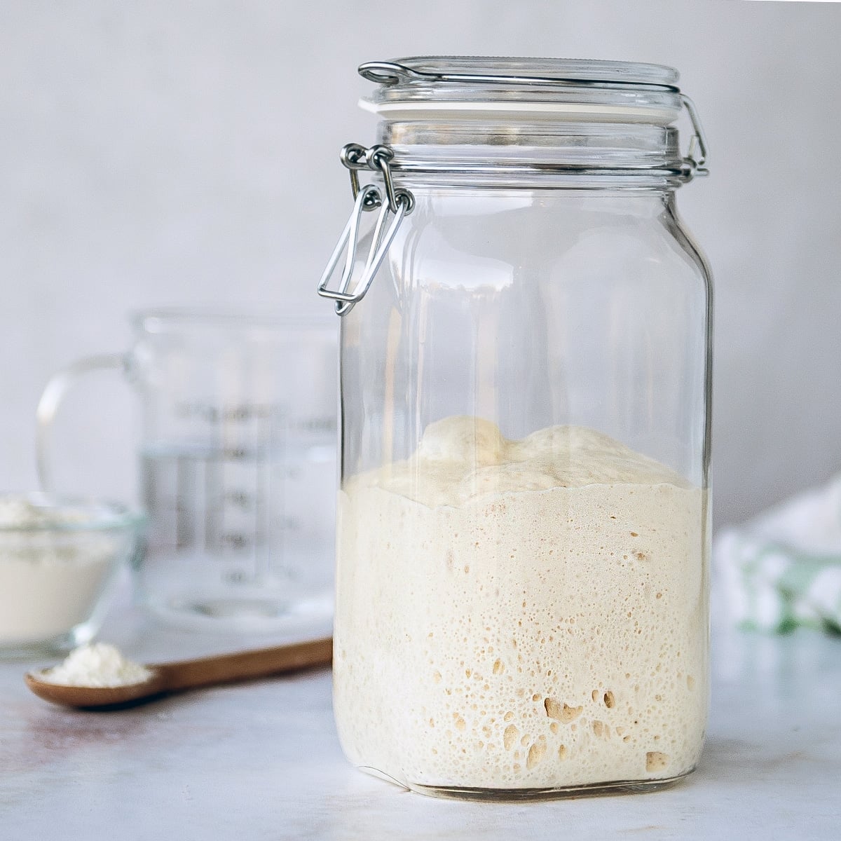 sourdough starter in a clear jar on white background