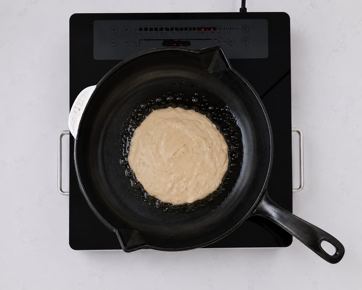 Sourdough pikelet batter in a hot cast iron pan.