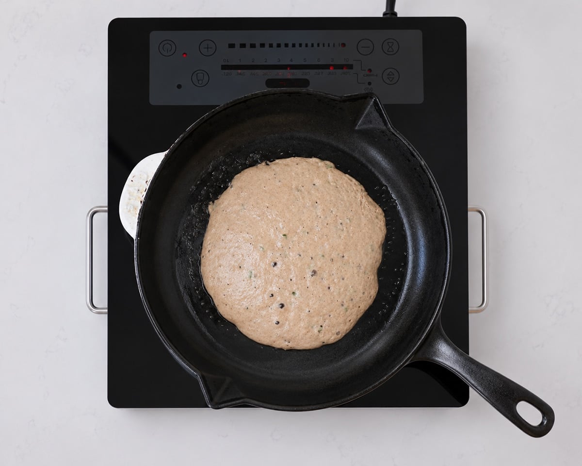 Sourdough pikelet batter in a hot cast iron pan.