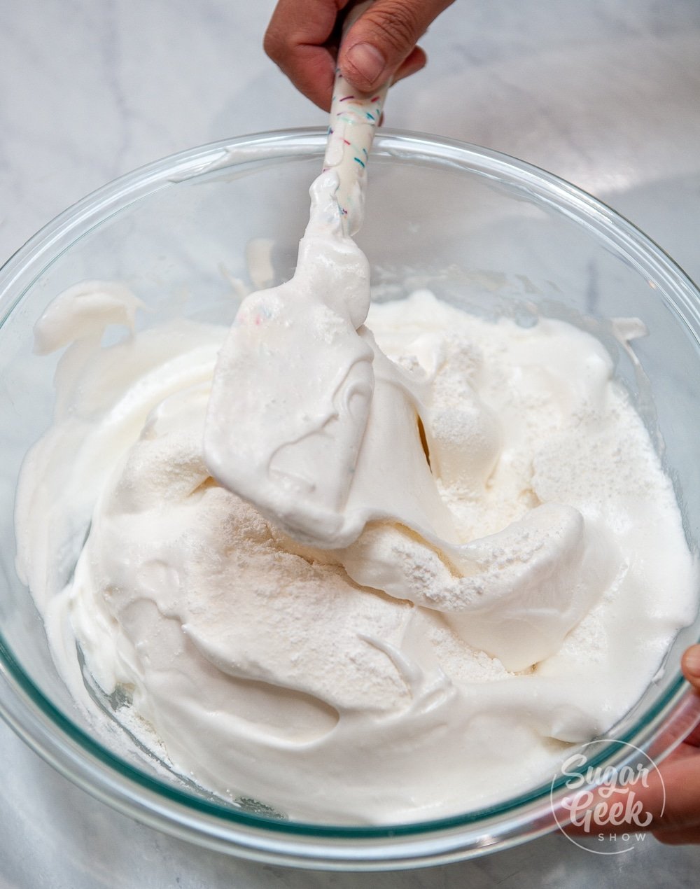 meringue in a clear bowl with a white spatula