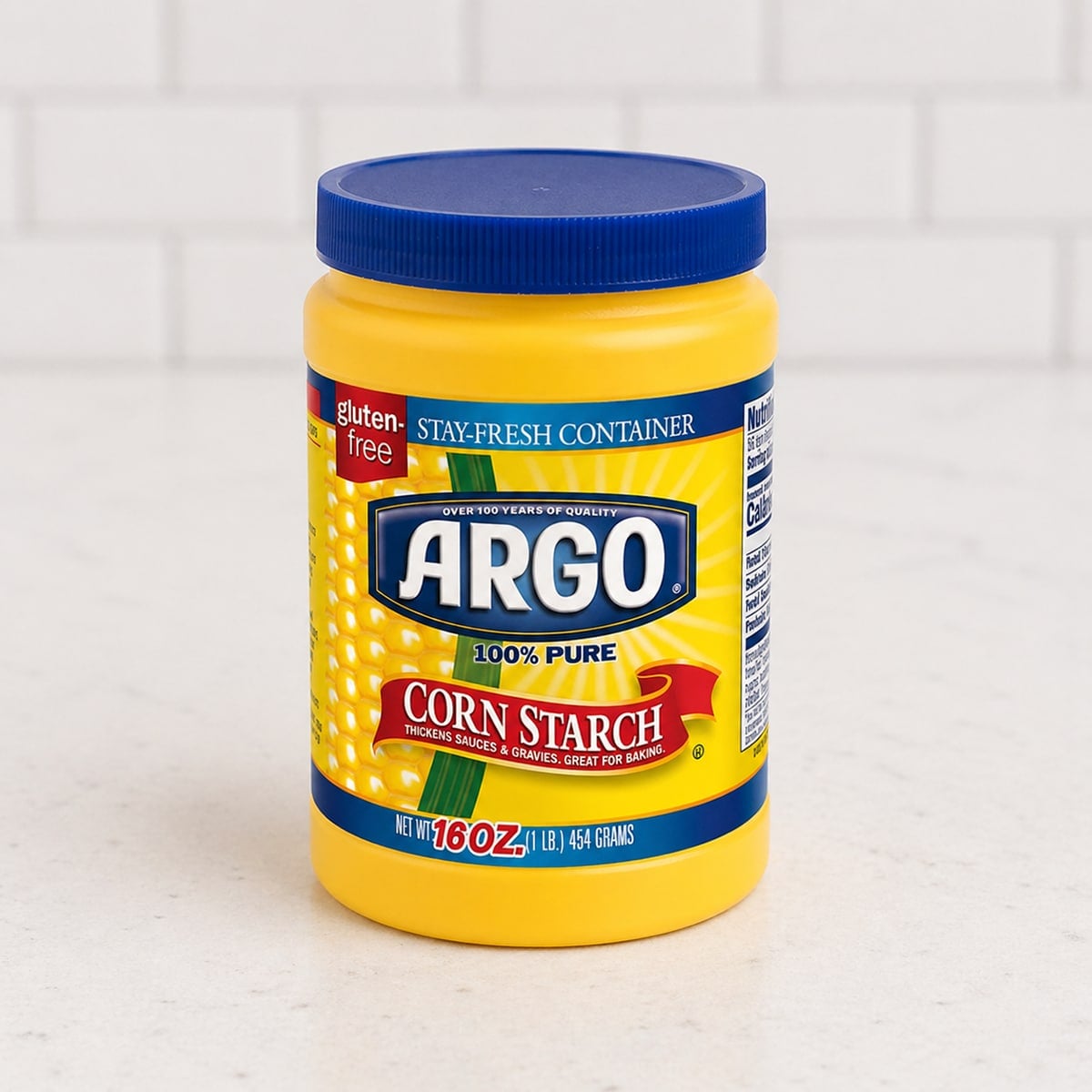 Container of cornstarch on a white countertop.